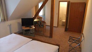 A bedroom with a bed, a TV, a chair, a small table, and a bathroom visible through an open door. - Gasthof Rotes Roß (Zell im Fichtelgebirge)