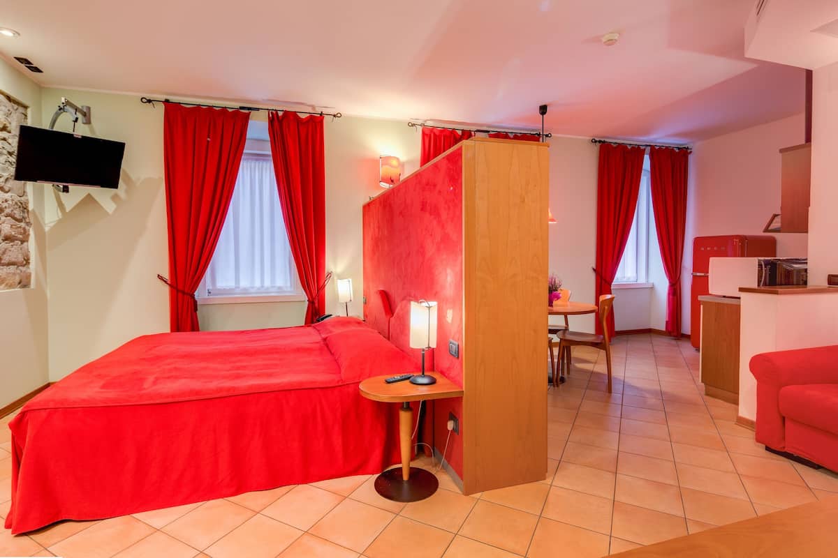 Une chambre d’hôtel avec un lit, un bureau, une chaise, une télévision et un canapé rouge.