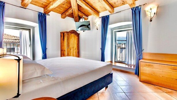 Un dormitorio con techo de madera, una cama, un aparador y un televisor en la pared.