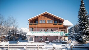 A wooden chalet with a balcony, snow-covered surroundings, and a clear sky. - Aparthotel Kristall (Altenmarkt im Pongau)