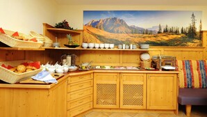 A cozy kitchen with wooden cabinets, a buffet setup, and a scenic mountain view. - Aparthotel Kristall (Altenmarkt im Pongau)