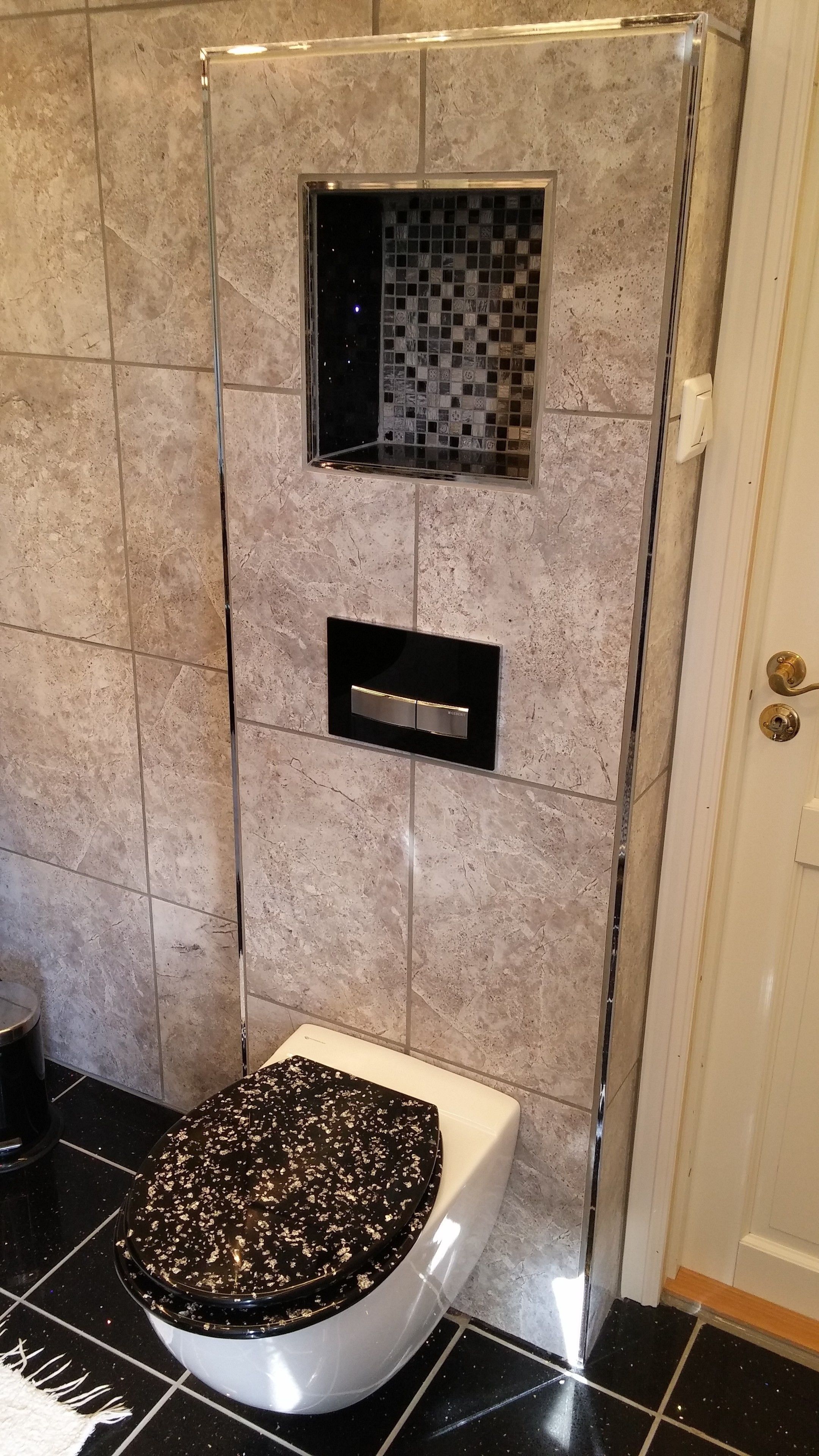 Un baño con inodoro, cabina de ducha y pared con azulejos.