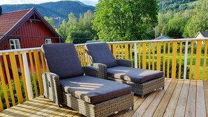 A wooden deck with wicker lounge chairs and a checkered floor. - Solheim Overnatting (Midt-Telemark)