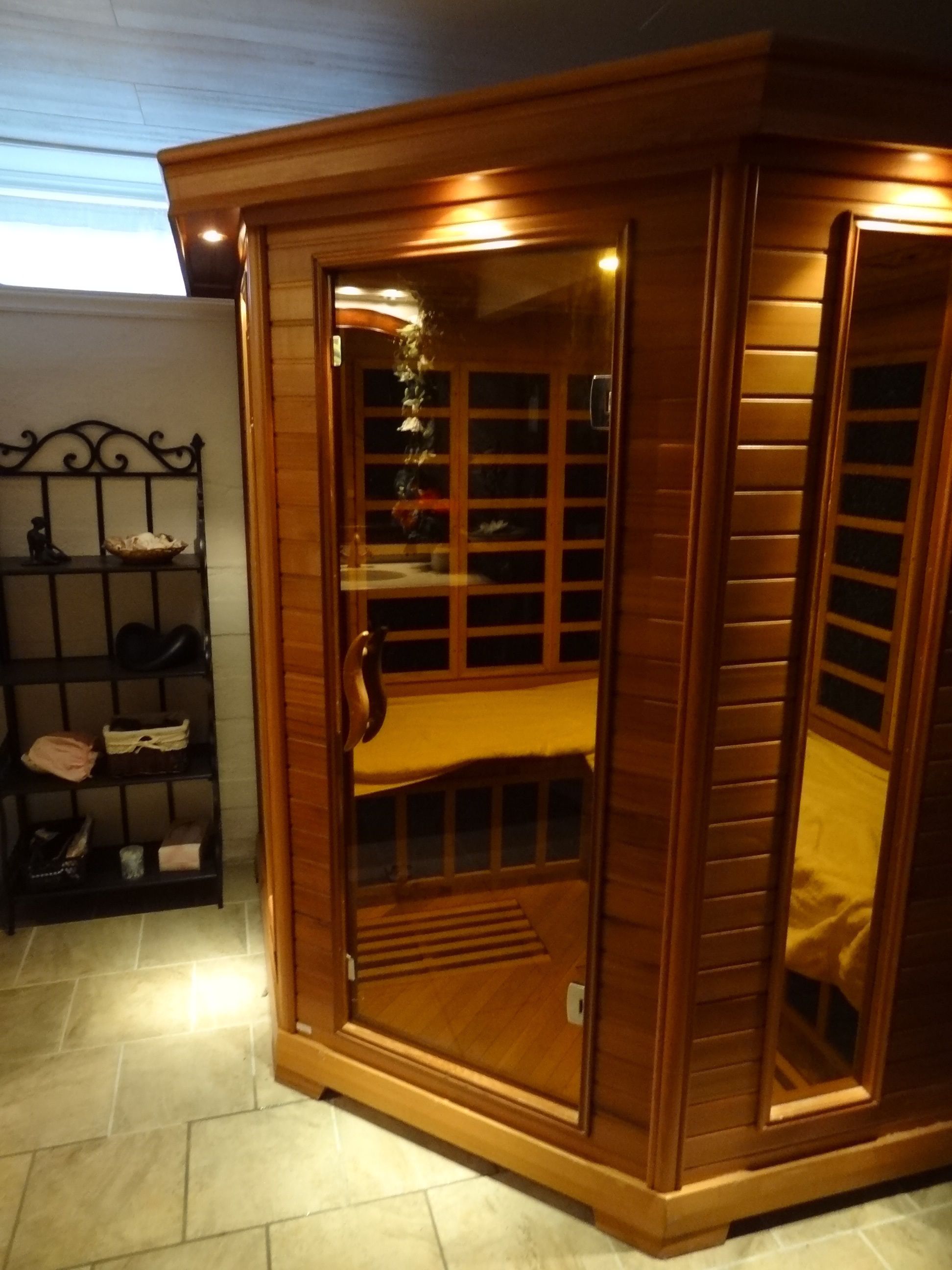 Un sauna avec une structure extérieure en bois, une porte en verre et une étagère à l’intérieur.