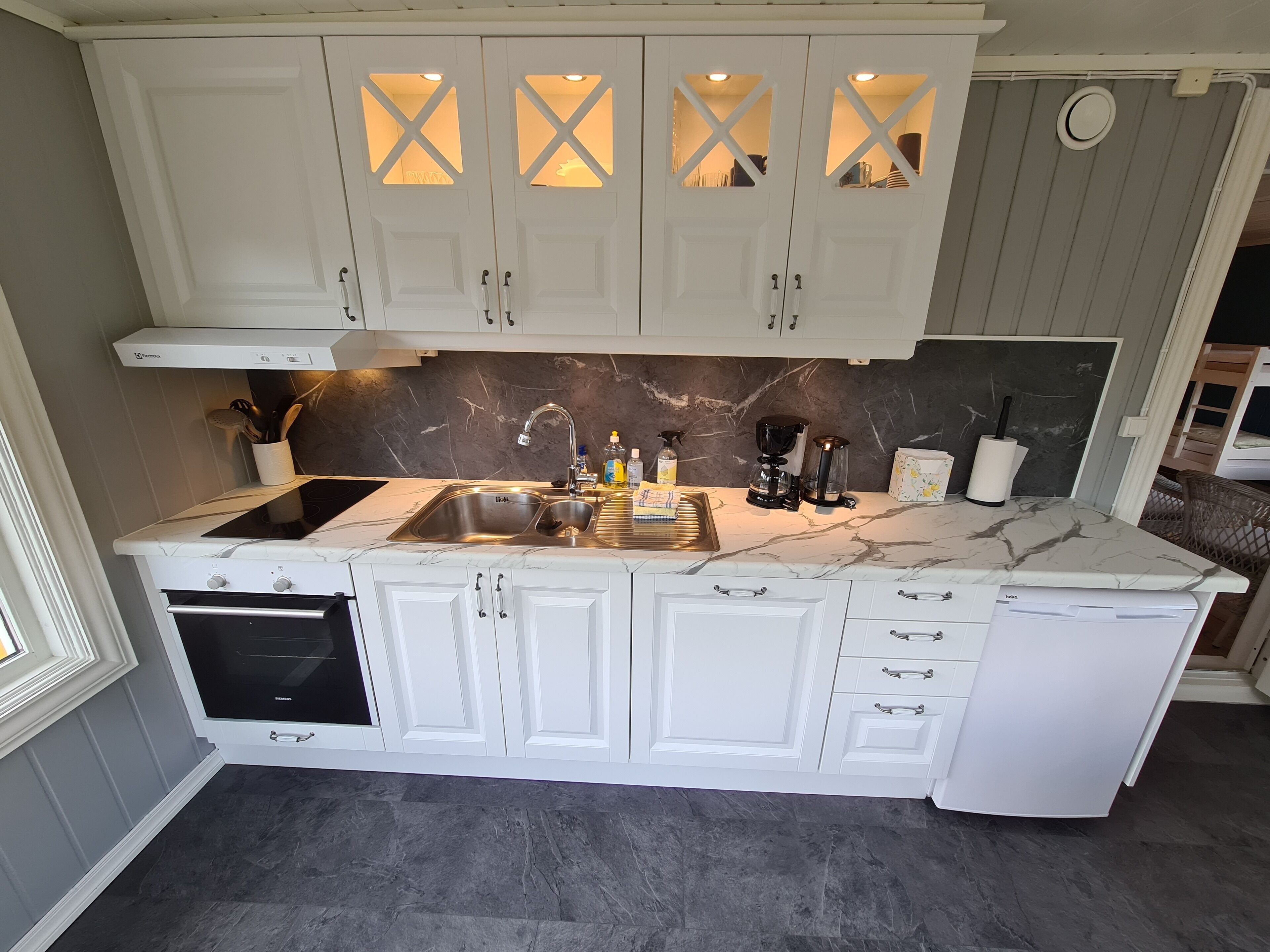 A kitchen with white cabinets, a marble countertop, and a built-in oven.