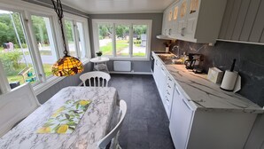 A kitchen with white cabinets, a marble countertop, and a view of the outdoors. - Solheim Overnatting (Midt-Telemark)