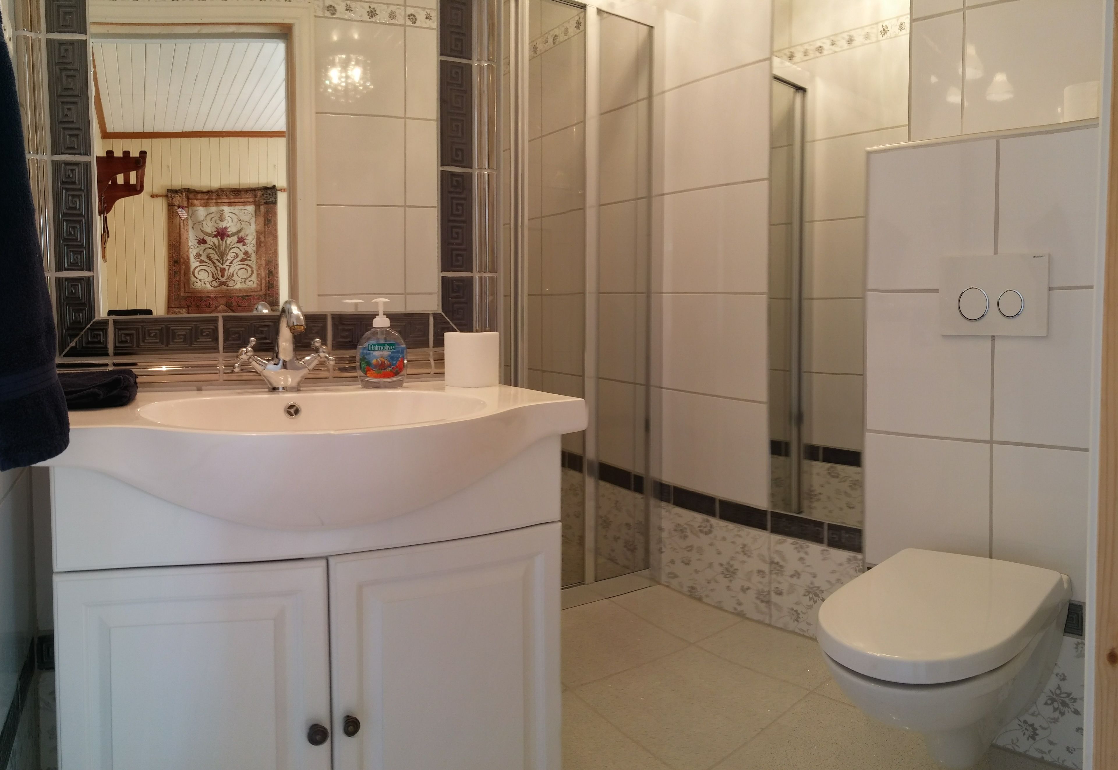 A bathroom with a white sink, mirror, and toilet.