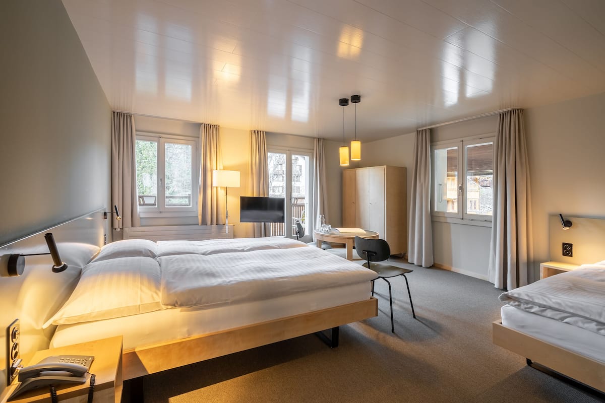 Ein Hotelzimmer mit zwei Betten, einem Schreibtisch, einem Fernseher und einem Kleiderschrank.
