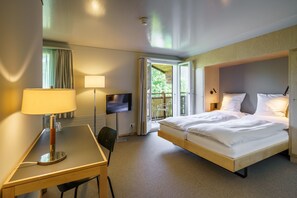 Habitación de hotel con cama, escritorio, televisión y balcón.