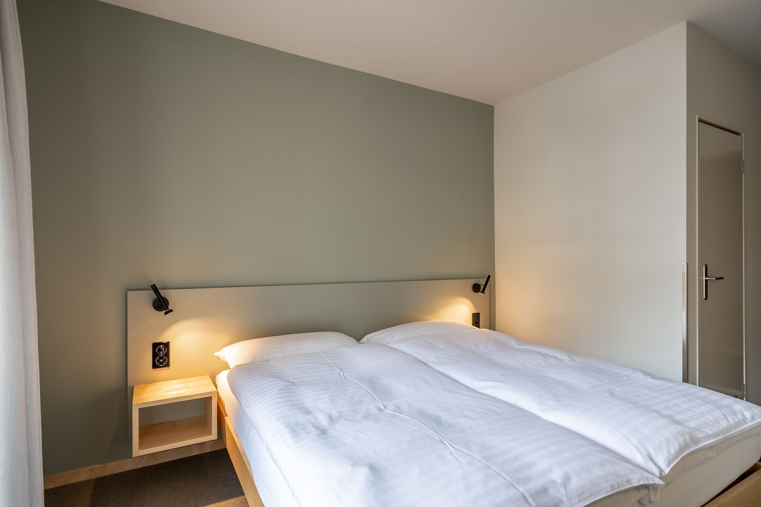 Cama bem arrumada em quarto com cabeceira e mesas de cabeceira simples.