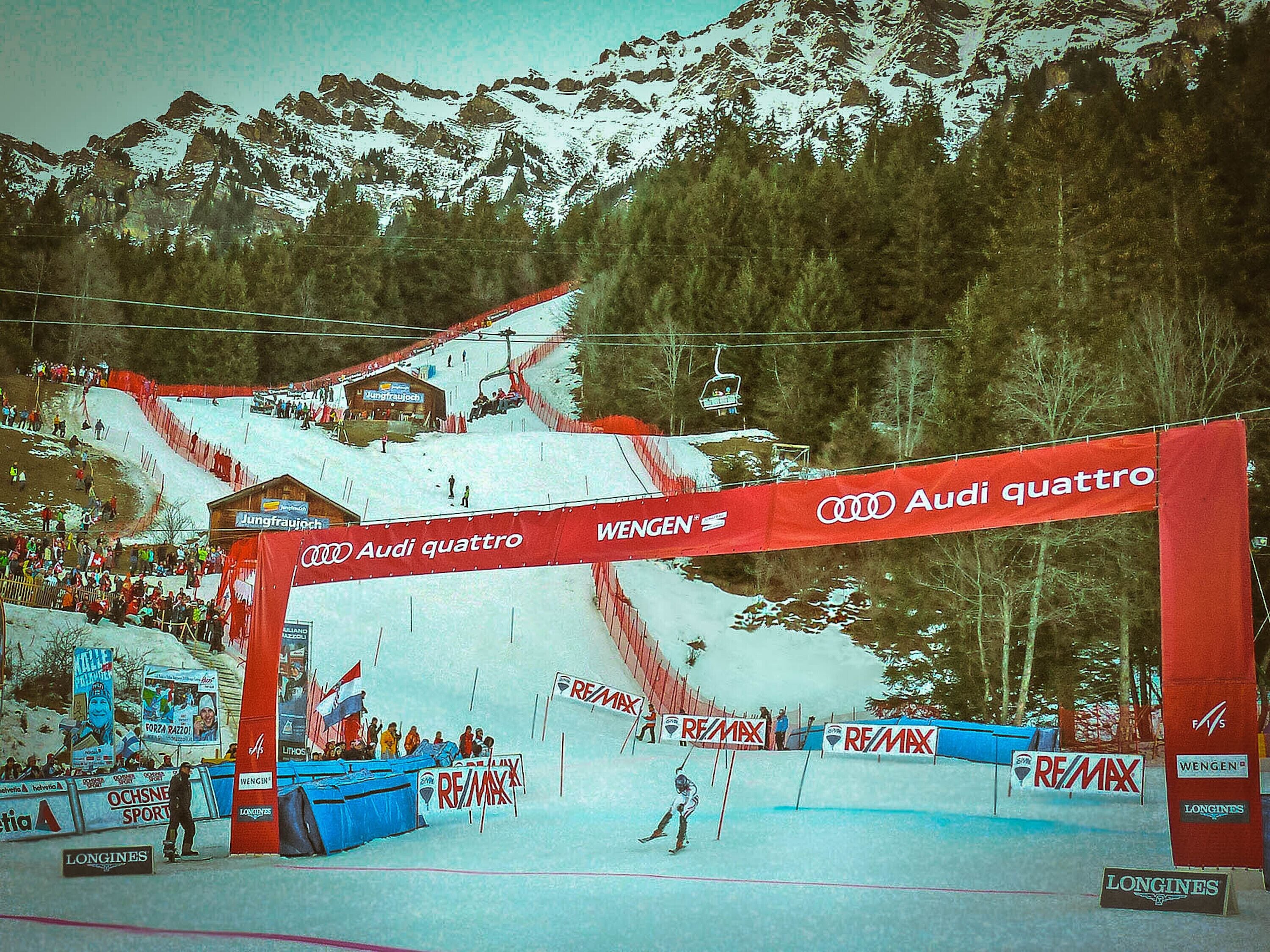 A ski slope with a red archway displaying the Audi quattro logo and the Wengen name.