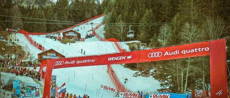 A ski slope with a red archway displaying the Audi quattro logo and the Wengen name.