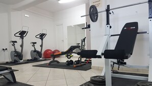 A gym with exercise equipment, including treadmills, a bench press, and a squat rack. - Romantica Apartments (Kithira)