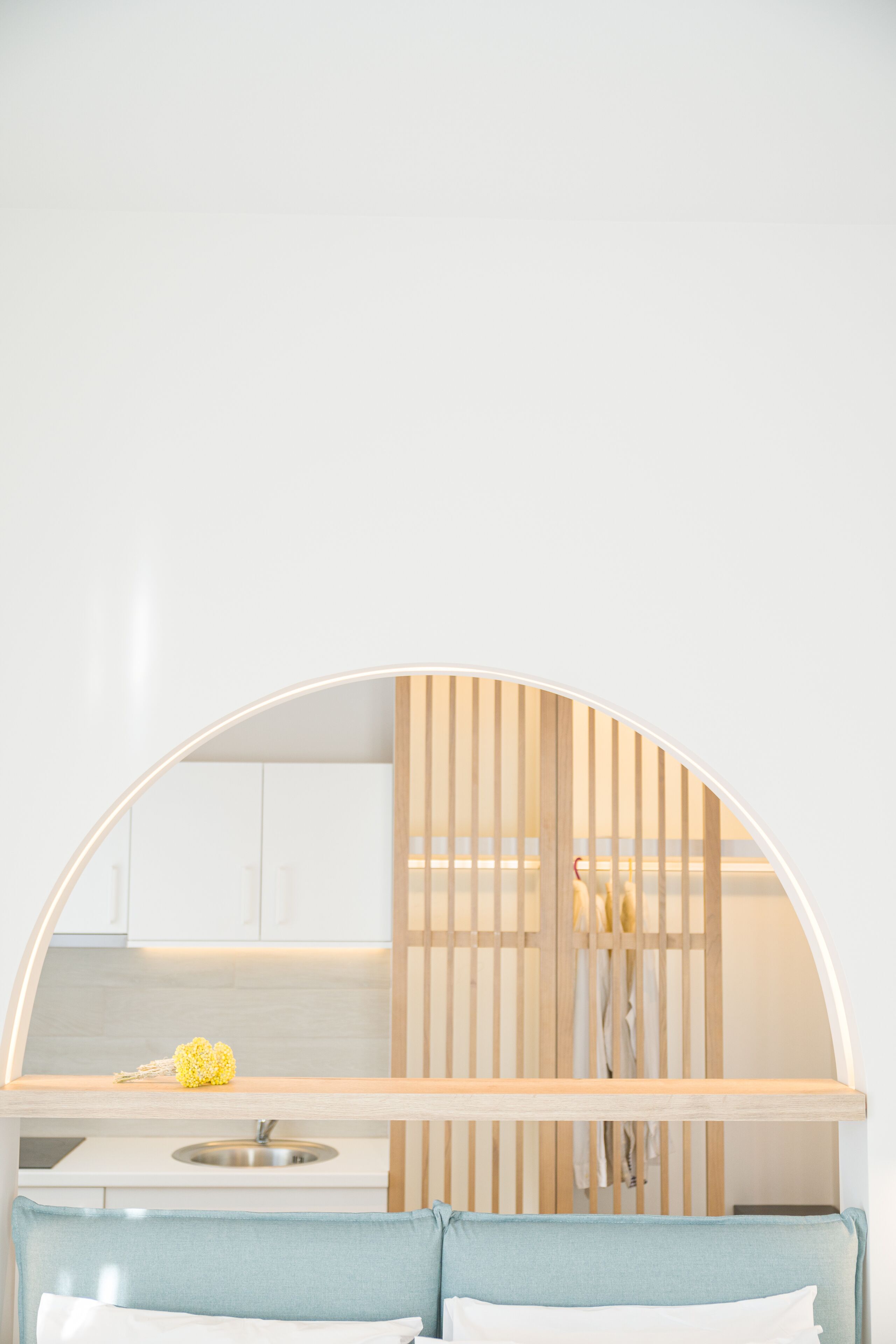 A compact kitchen with a built-in bench, a sink, and a wooden slatted partition.