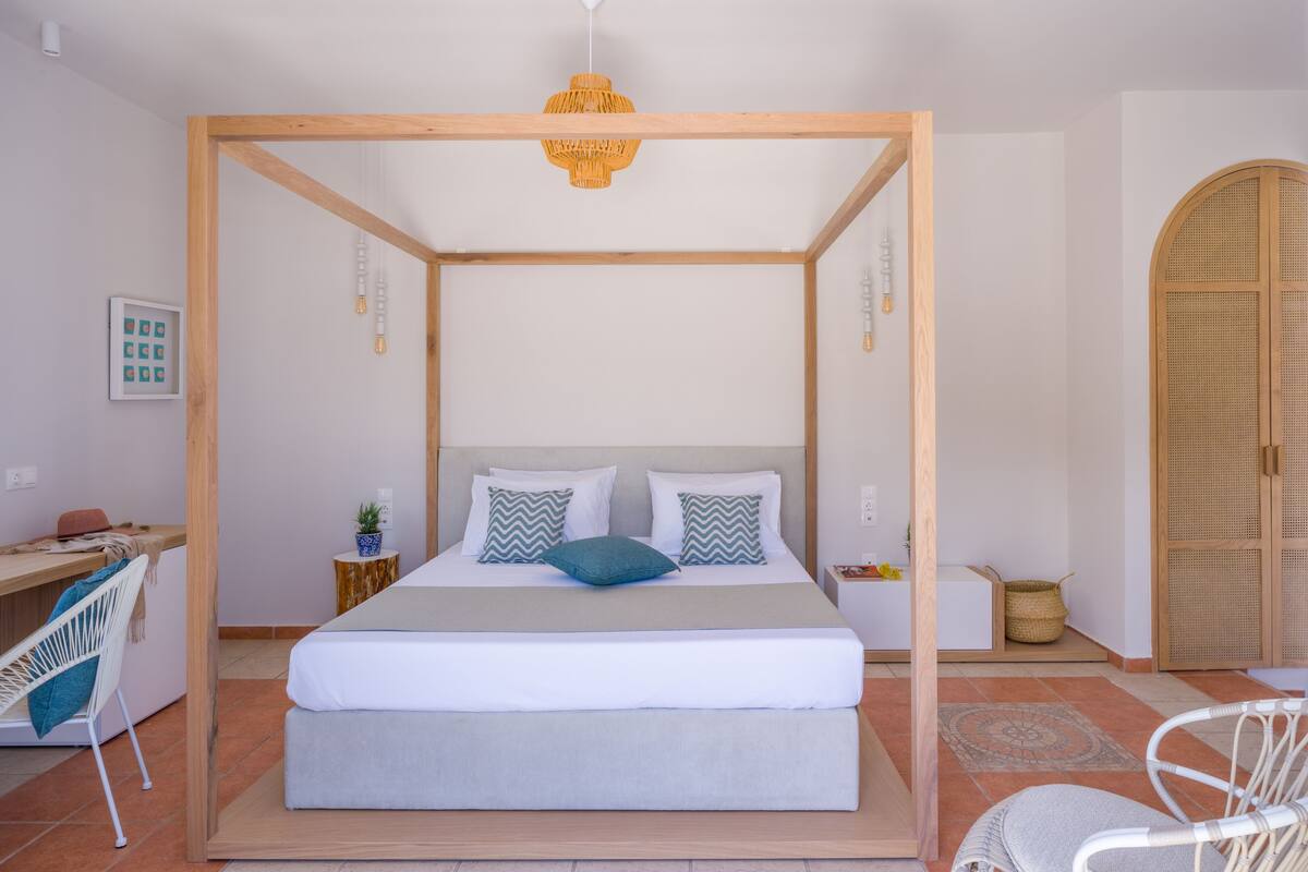 A bedroom with a four-poster bed, a desk, a chair, and a wardrobe.
