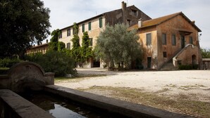 A historic building with a courtyard, a small water feature, and a staircase leading to the entrance. - Agriturismo Pantano Borghese (Rome)
