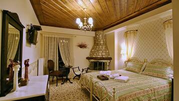 A bedroom with a stone fireplace, a bed with green bedding, a wooden ceiling, and a mirror on the wall.