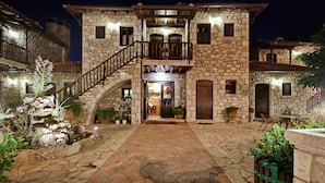 A stone building with a central entrance, a staircase, and a balcony.