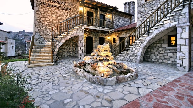 A stone building with a central fountain, a staircase, and a balcony.