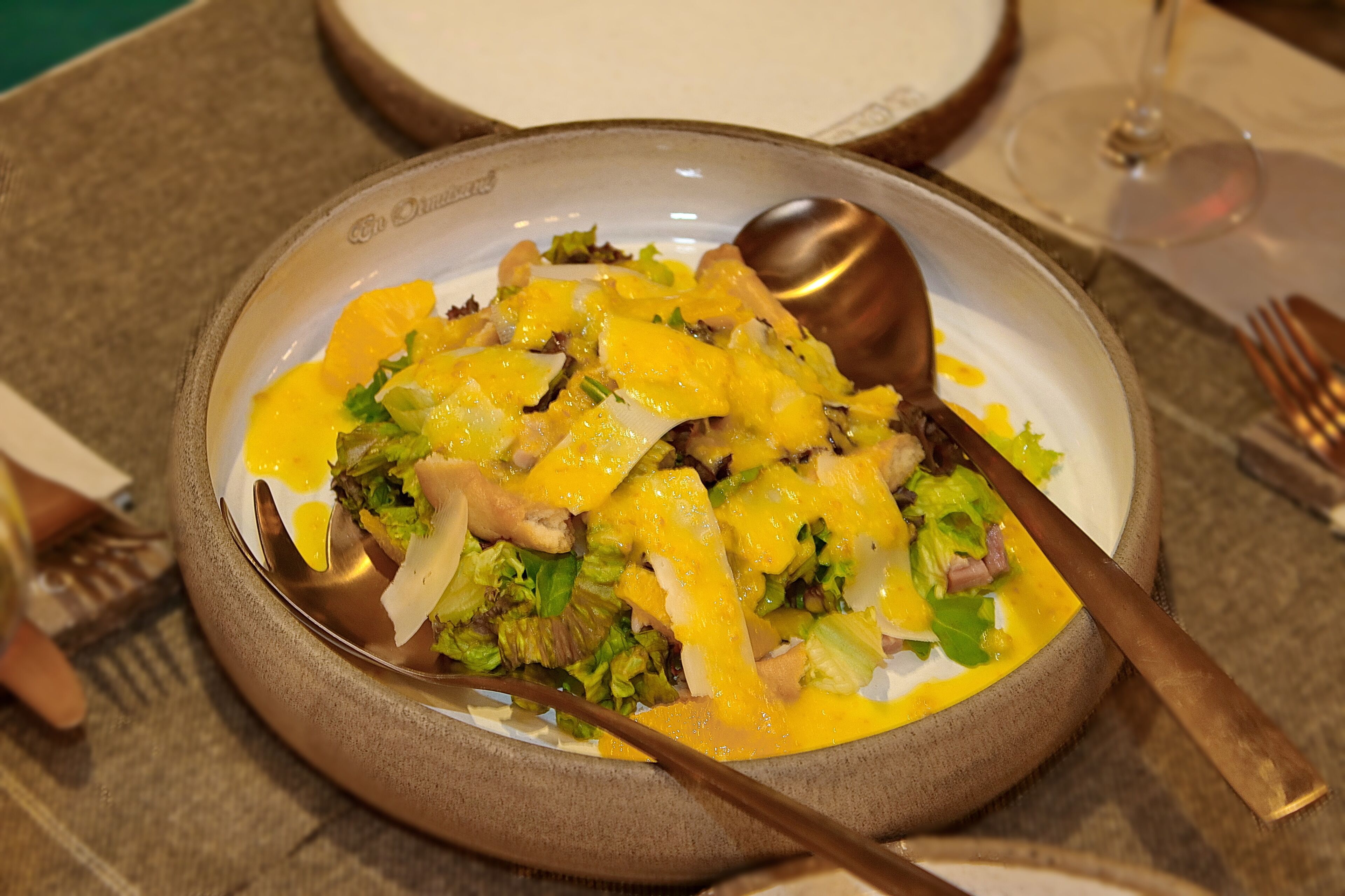 A bowl of salad with a spoon on a table.