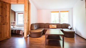 A spacious living area with a large sectional sofa, a wooden table, and a bed with a striped blanket.