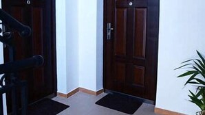 Two dark wooden doors with a metal handle, a white wall, and a tiled floor.