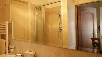 Une salle de bain avec un grand miroir, un lavabo, une douche et un porte-serviettes.