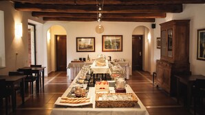 A buffet setup with various food items and beverages, wooden furniture, and arched doorways. - Villa Acquaviva Wine Resort (Manciano)