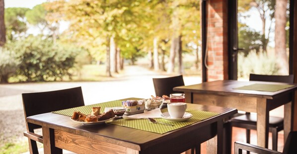 Un área de comedor al aire libre con una mesa lista para el desayuno, incluyendo pastelería y una taza de café.