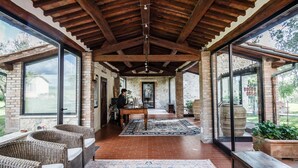 A covered patio area with wicker furniture, a wooden table, and a large rug. - Villa Acquaviva Wine Resort (Manciano)