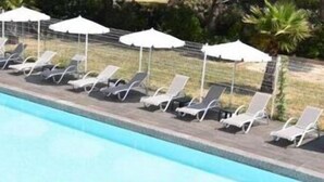 Une piscine avec des chaises longues et des parasols.