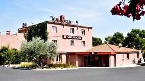 Un hôtel appel é « Qualys Hotel », doté d’un toit recouvert de tuiles rouges et d’une enseigne indiquant « Le Mas de la Grive ».