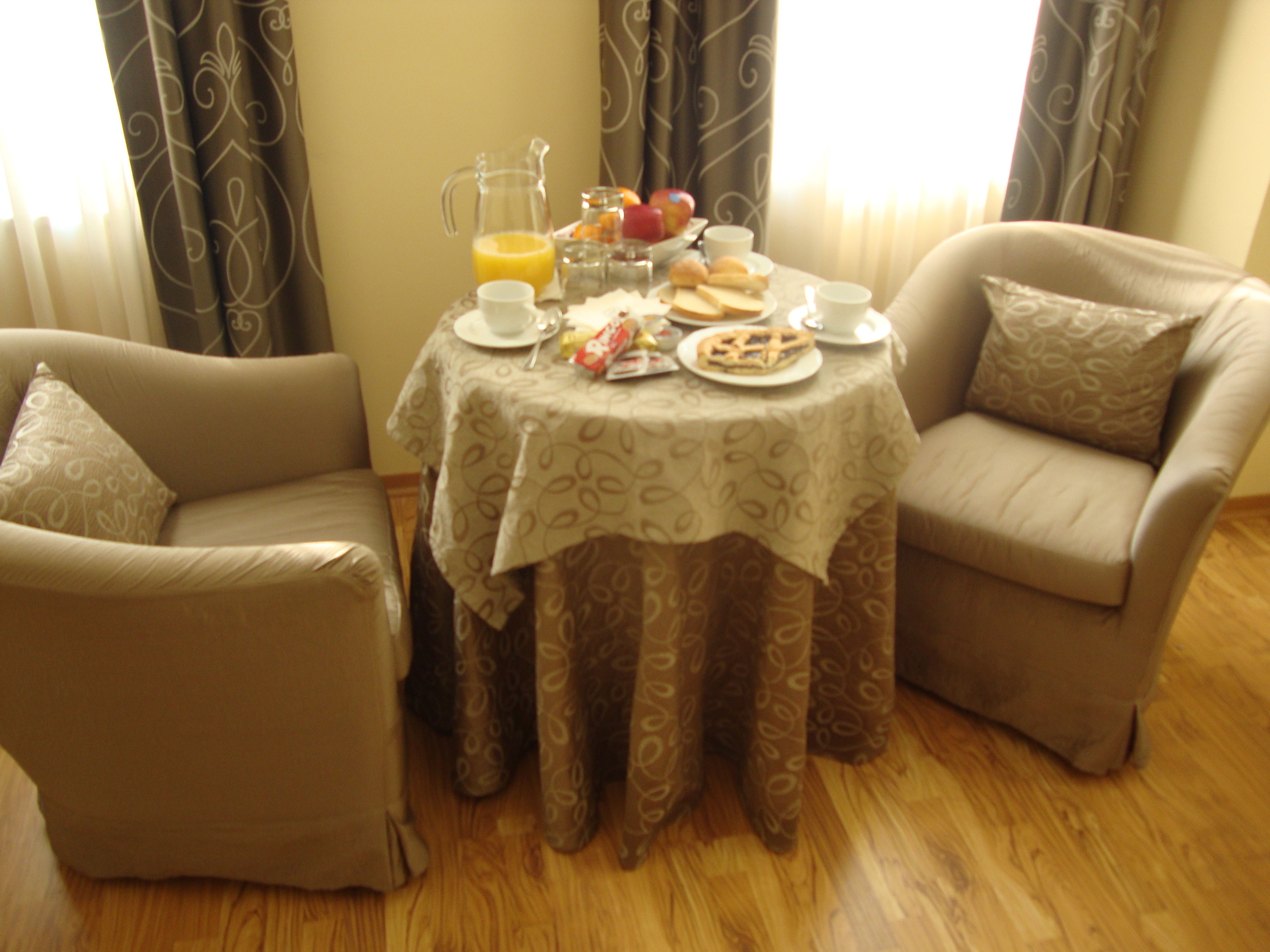 A dining area with a table set for breakfast, including a pitcher of orange juice, a fruit bowl, and plates of food.