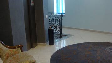 A spacious room with a large round carpet, a sofa with floral upholstery, and a door leading to another area.