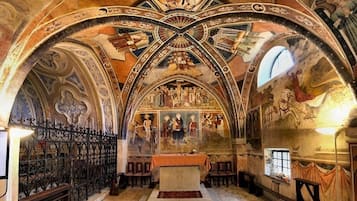 An interior with arched ceilings, a central altar, and detailed frescoes.