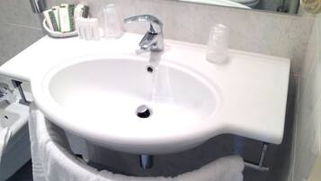 Un bagno con lavandino bianco, specchio e articoli da toilette sul ripiano.