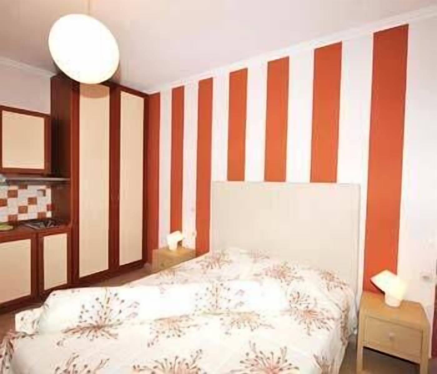 A bedroom with a bed, nightstands, a dresser, and a mirror.