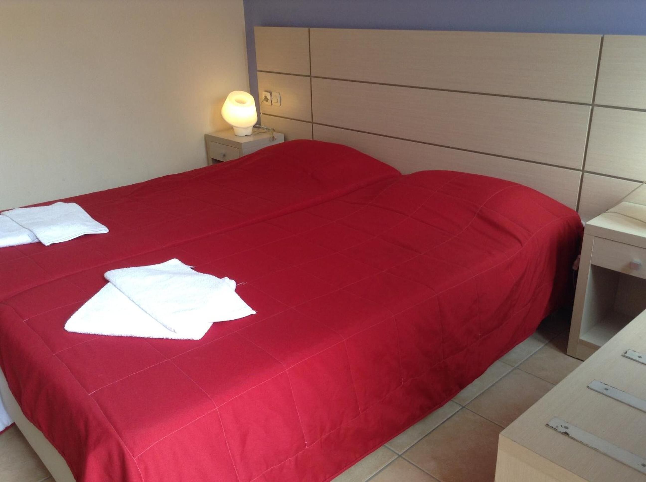 A hotel room with a bed, a nightstand with a lamp, and a small table.