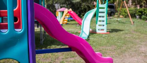 A playground with a pink slide and various play structures.