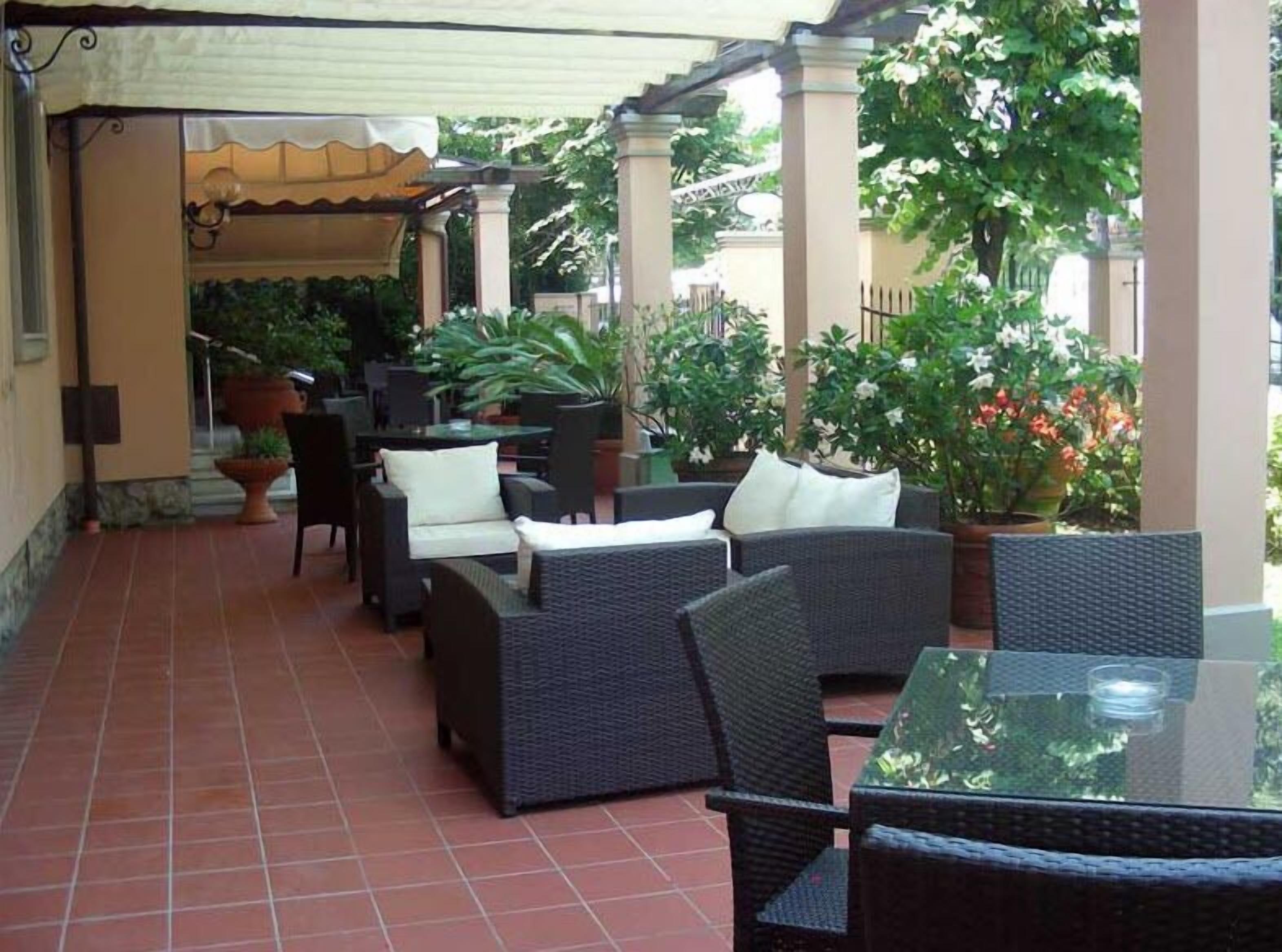 An outdoor patio with wicker furniture, potted plants, and a tiled floor.