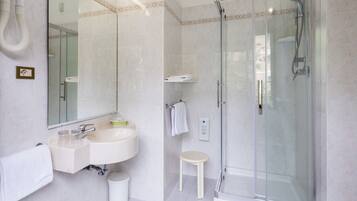 Een moderne badkamer met een douchecabine van glas, een wastafel met spiegel en een toilet.