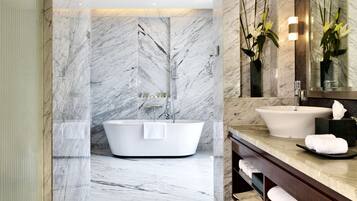 Un baño moderno con una bañera independiente, un tocador con lavabo y un espejo grande.