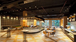A modern restaurant with a central bar, seating areas, and a view of the outdoors.