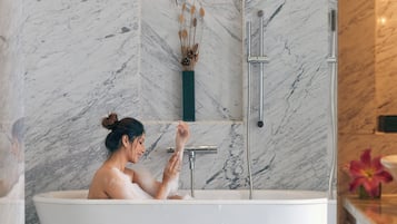 A modern bathroom with a freestanding bathtub, marble walls, and a minimalist design.