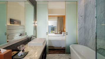A modern hotel bathroom with a large mirror, a bathtub, a sink, and a shower.