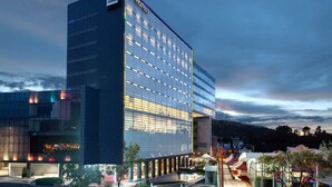 Un hotel moderno con fachada de vidrio, varios pisos y una señalización llamativa.
