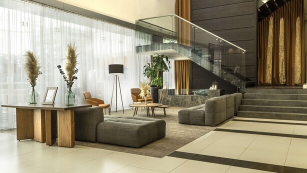 Un vestíbulo moderno con una escalera de cristal, zona de estar y mostrador de recepción.