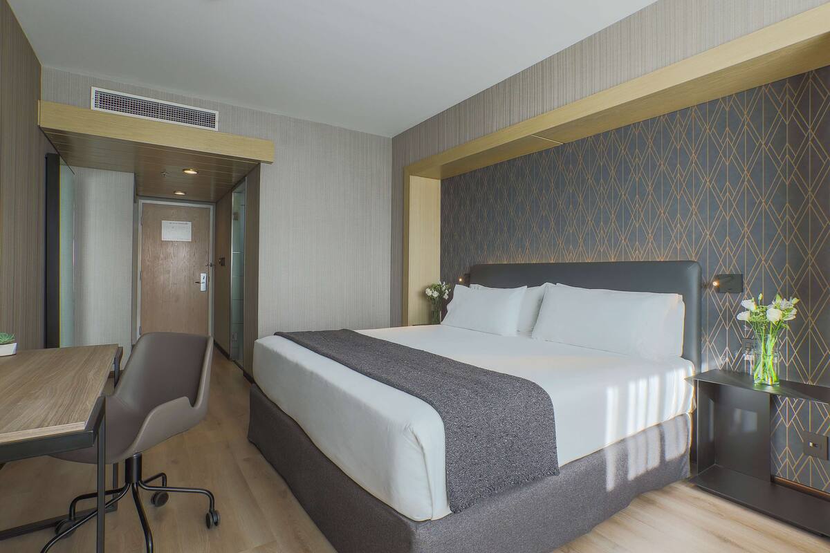 Ein Hotelzimmer mit einem Bett, einem Schreibtisch und einem Stuhl.