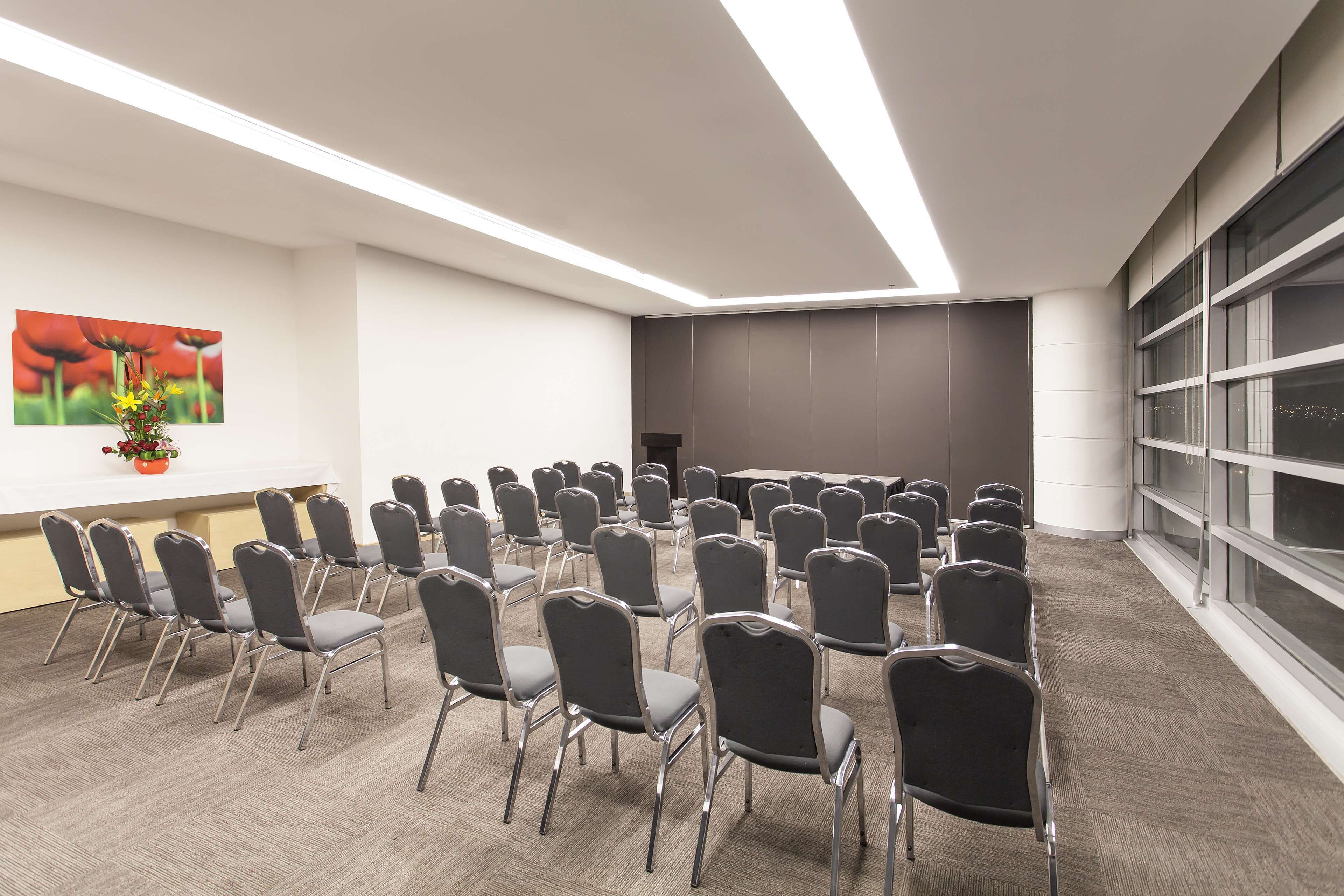 A conference room with rows of chairs, a whiteboard, and a painting on the wall.