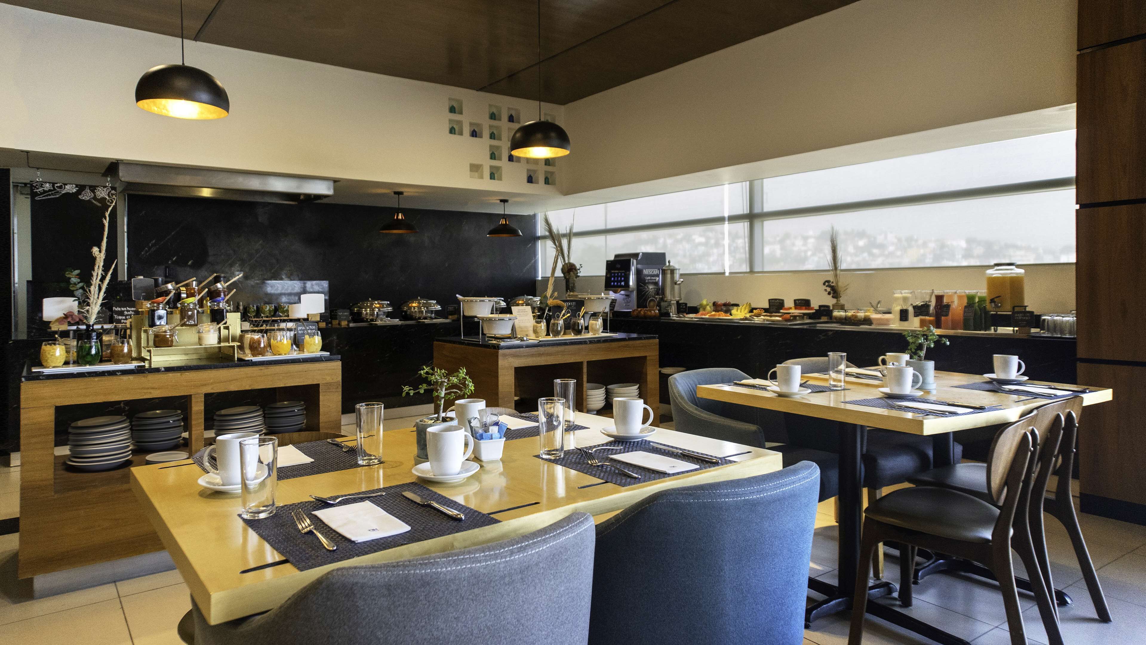 A modern restaurant with a bar area, dining tables set with white tableware, and a view of the city through large windows.